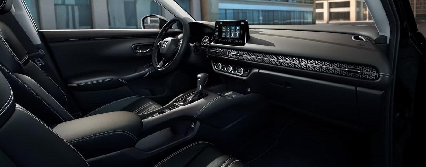 The black interior of a 2024 Honda HR-V EX-L shows the infotainment screen and dash.