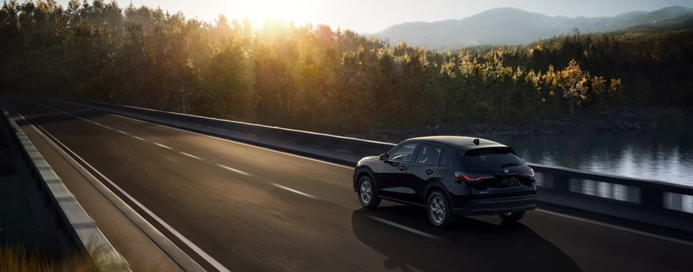 A black 2024 Honda HR-V LX is shown driving on a bridge.