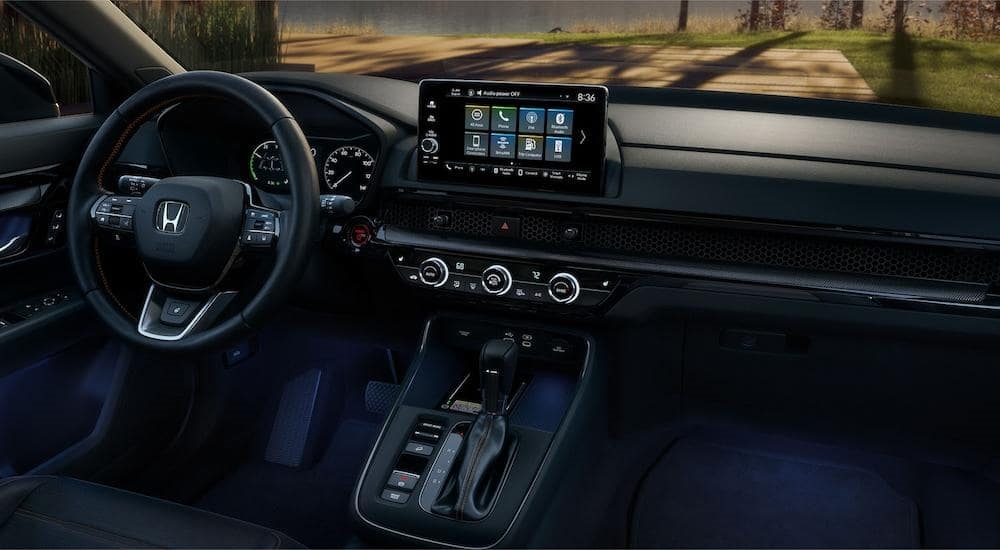 The black interior of a 2023 Honda CR-V Touring Sport shows the steering wheel and center console.