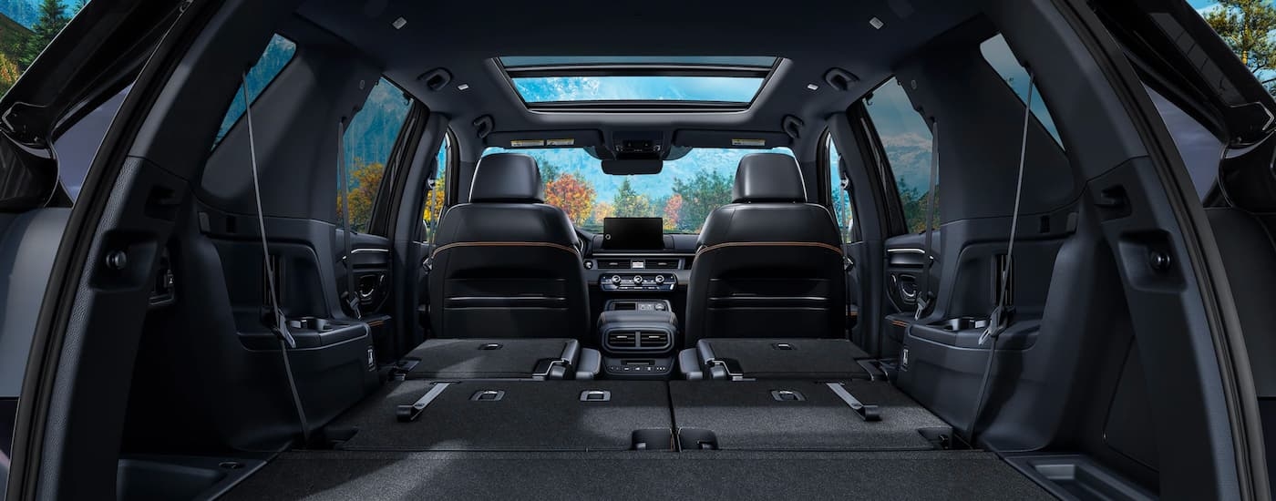 The black interior of a 2023 Honda Pilot Trailsport is shown with the seats folded down.