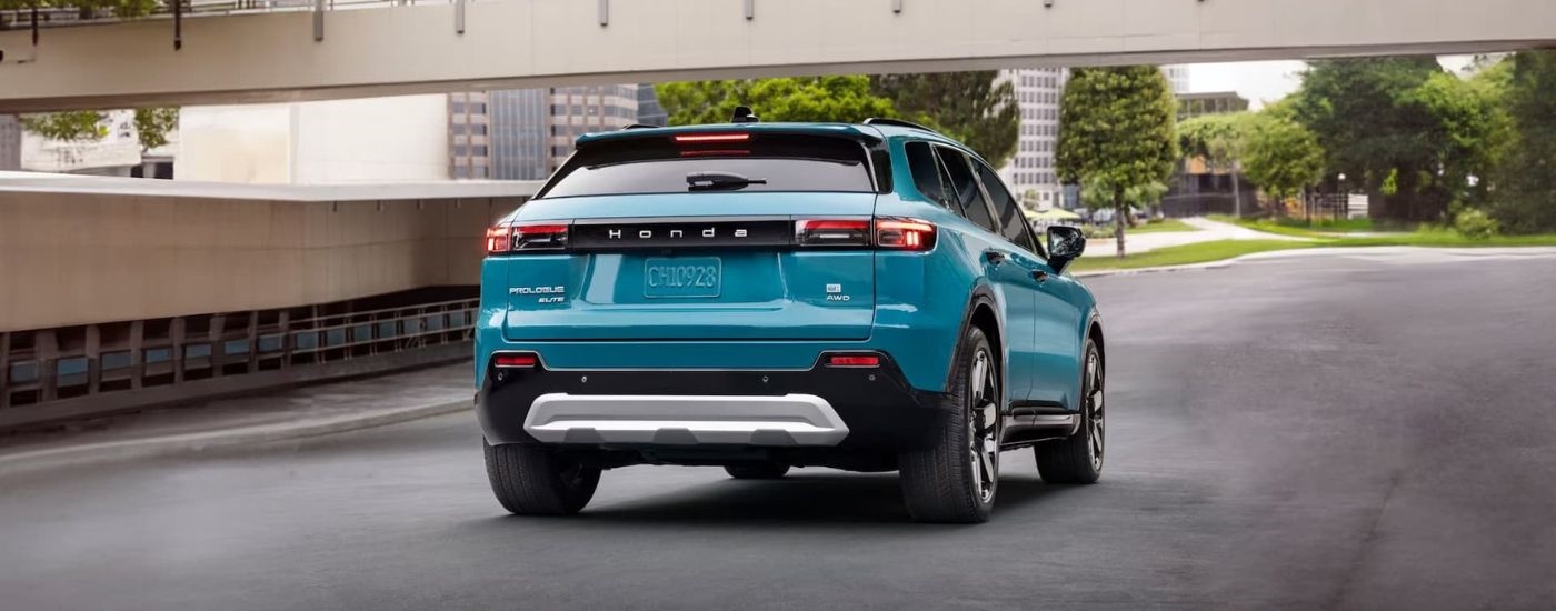 A blue 2024 Honda Prologue Elite is shown from the rear driving on a highway.