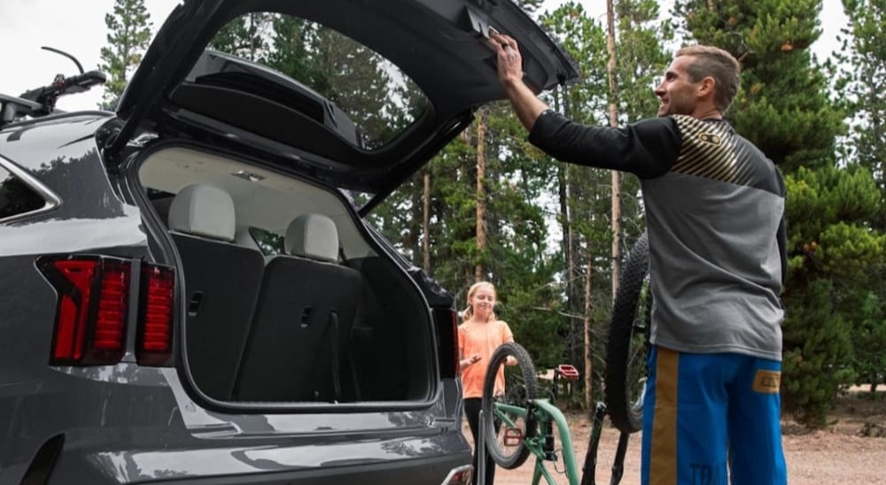 A person opening the hatchback of a grey 2024 Kia Sorento Hybrid.