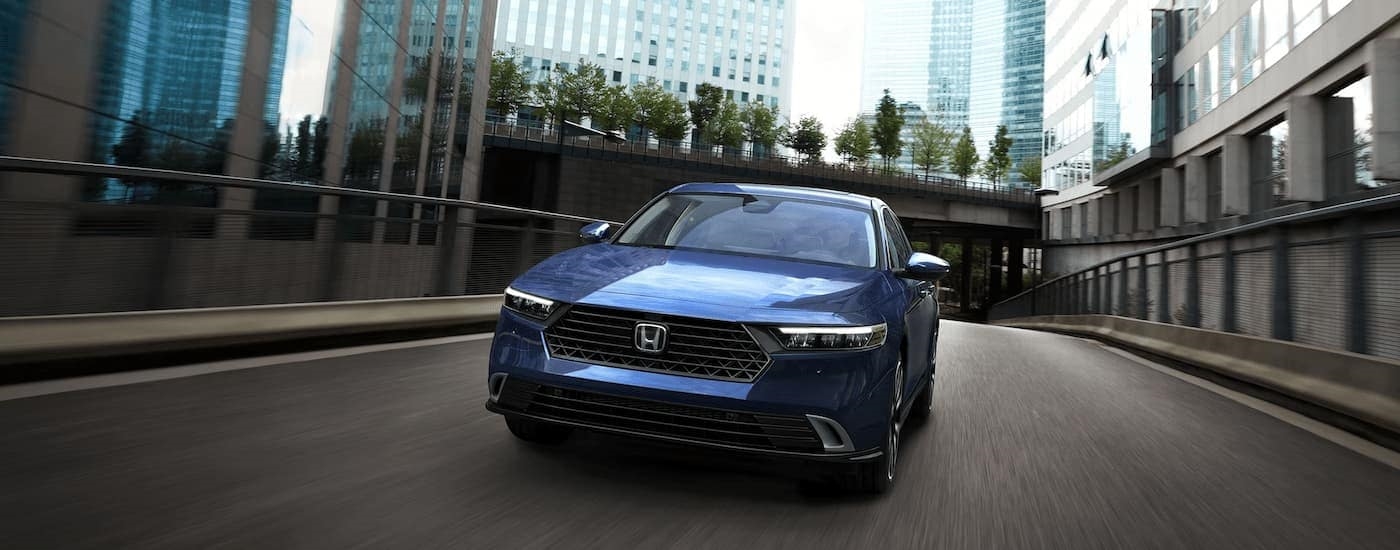  A blue 2023 Honda Accord Sport Hybrid is shown from the front driving on a highway.