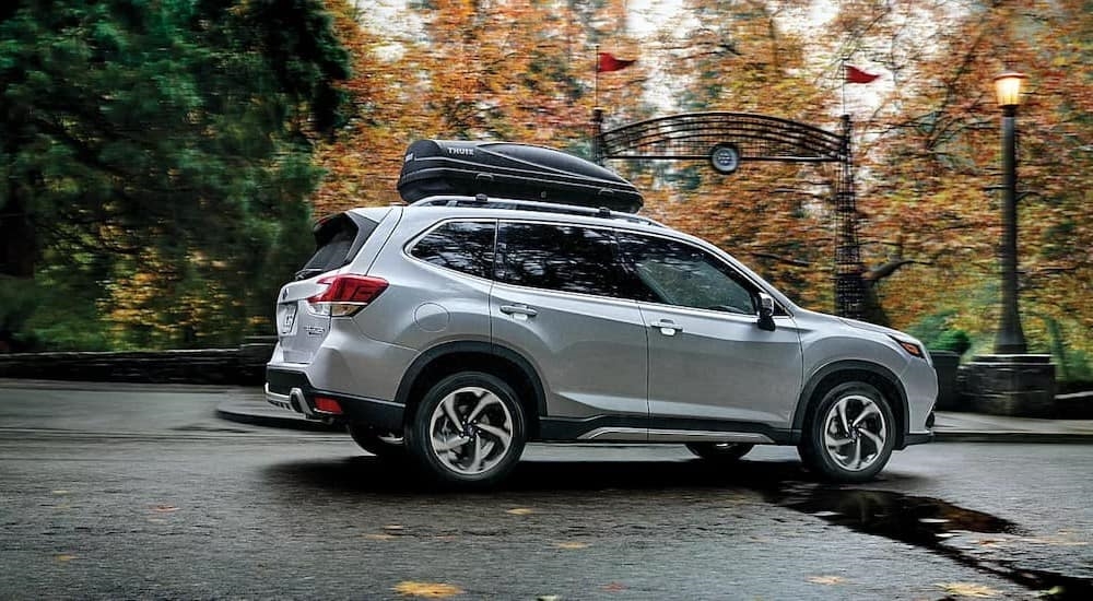 A silver 2024 Subaru Forester is shown driving near a park.