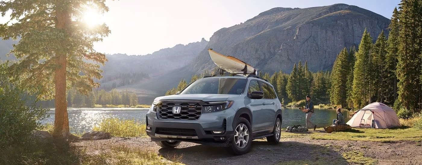 A blue 2023 Honda Passport TrailSport is shown near a lake.