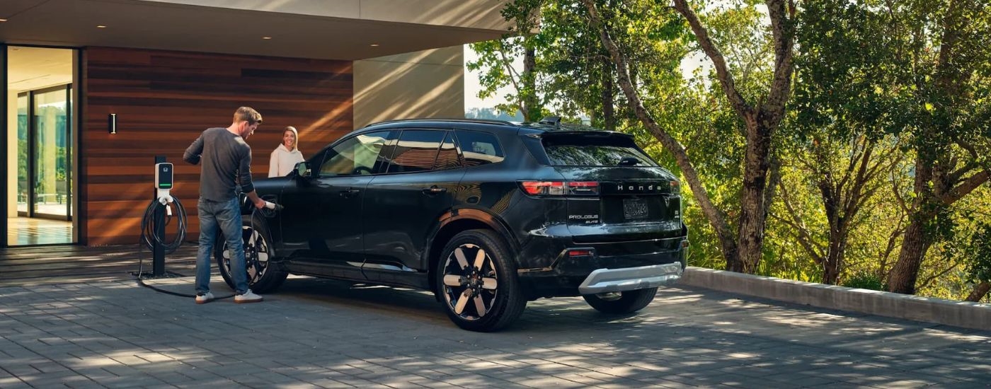 A black 2024 Honda Prologue Elite is shown charging parked on a driveway.