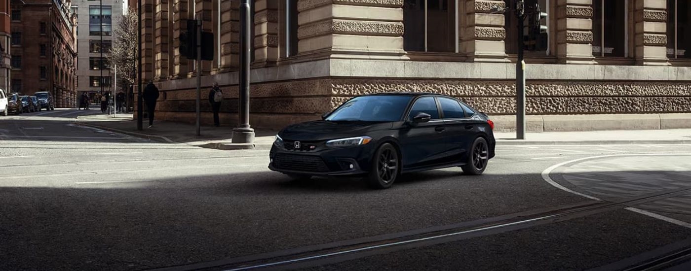 A black 2023 Honda Civic Si is shown driving through an intersection.