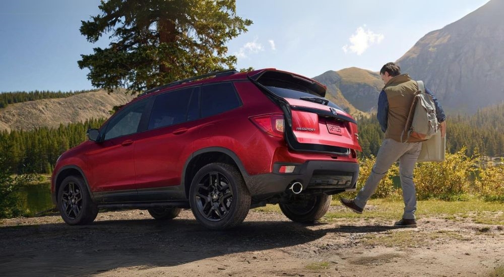 A person is shown loading a bag into a red 2024 Honda Passport.