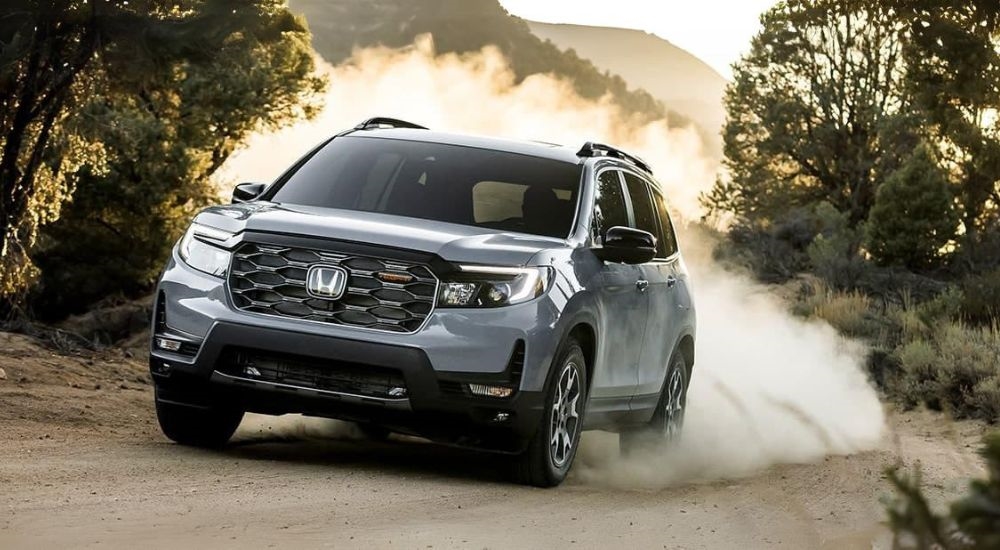 A silver 2024 Honda Passport TrailSport is shown kicking up dust.