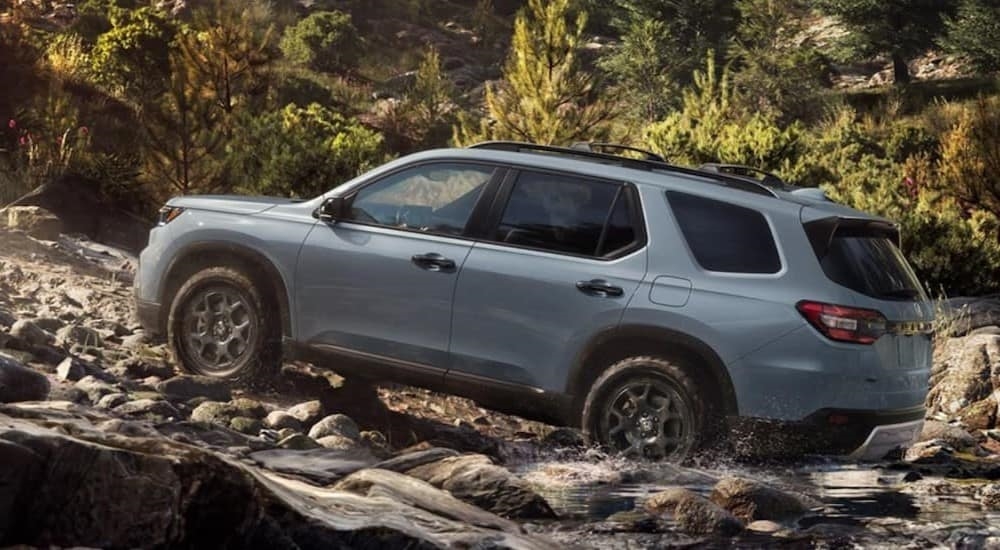 A gray 2023 Honda Pilot is shown driving off-road.