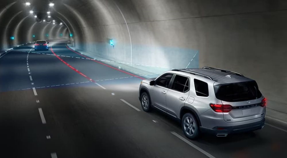 A silver 2025 Honda Pilot Spor is shown driving through a tunnel.