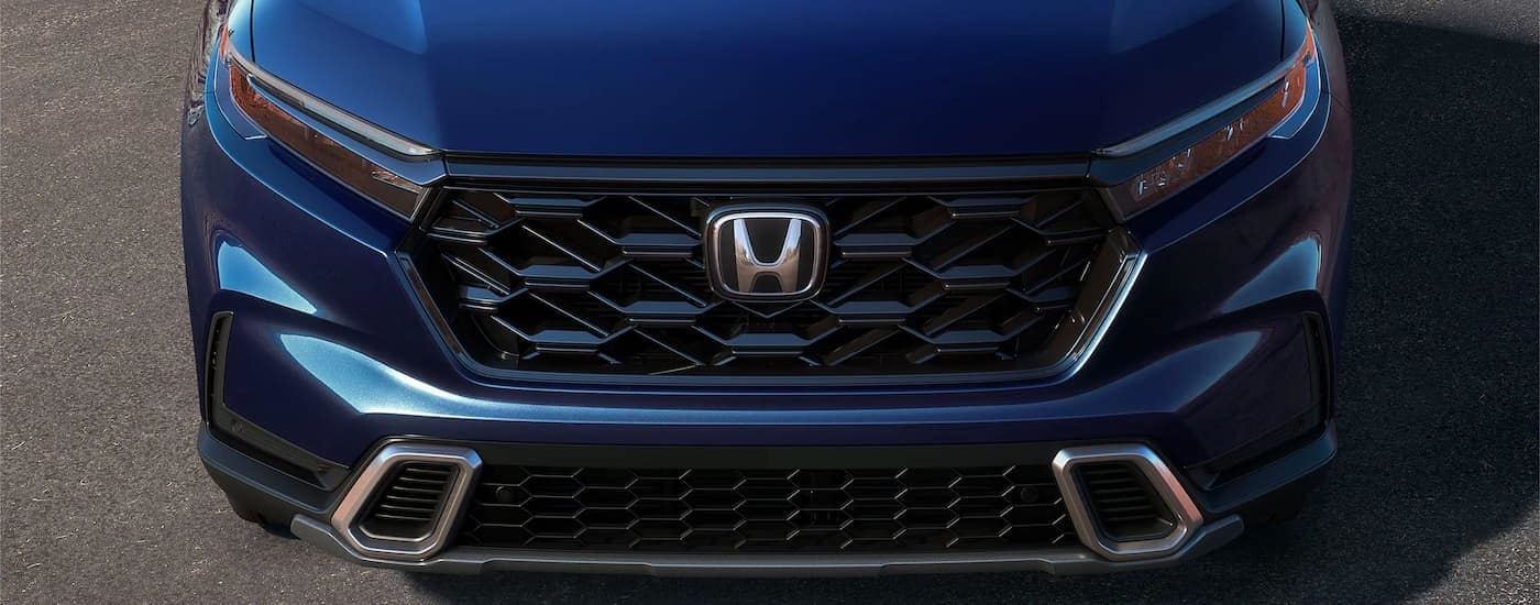 A close up shows the grille and headlights on a dark blue 2023 Honda CR-V Hybrid Sport Touring.