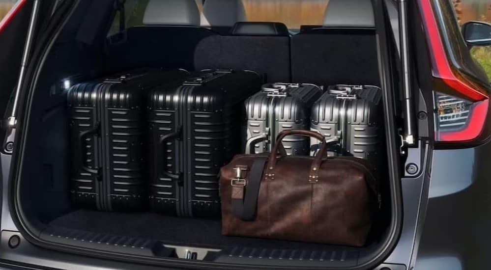 Suitcases in the rear cargo area of a black 2024 Honda CR-V ST Hybrid.