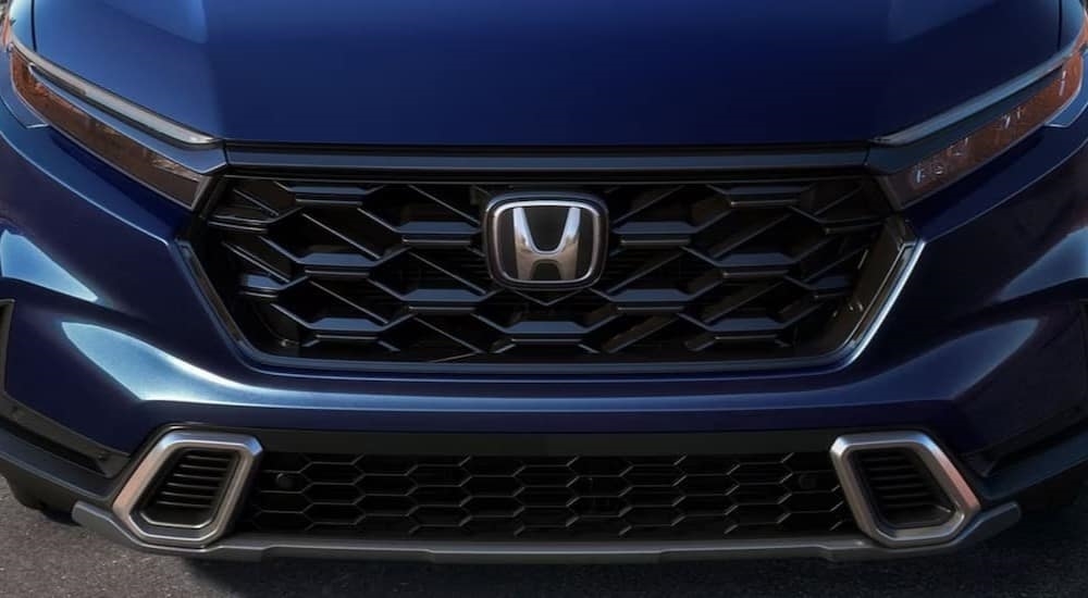 A close-up of the grille on a blue 2024 Honda CR-V Sport Touring Hybrid is shown.