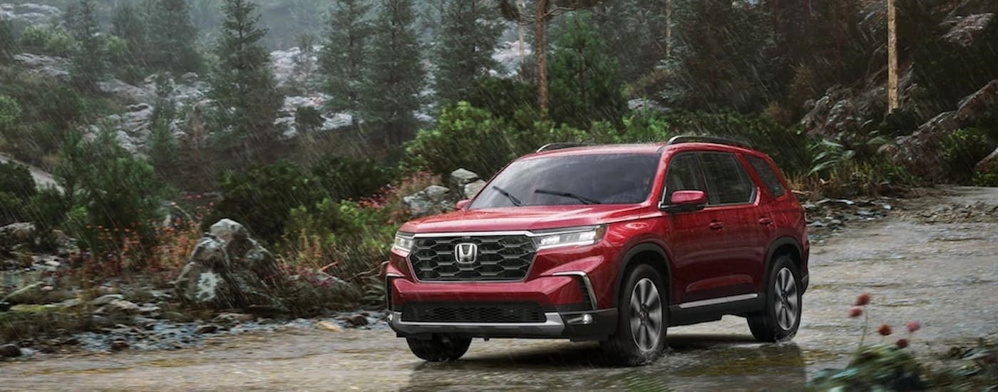 A red 2023 Honda Pilot is shown from the front at an angle.