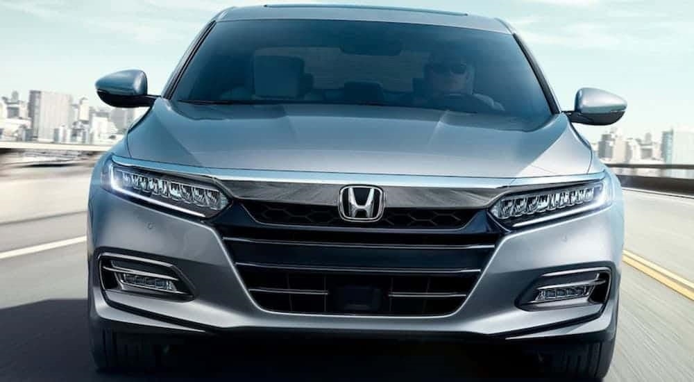 A silver 2020 Honda Accord Touring is shown driving near a city.
