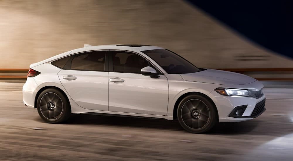 A white 2024 Honda Civic Hatchback is shown driving in a tunnel.