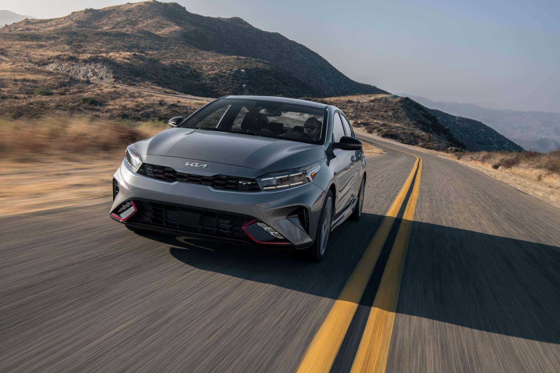 New Kia Forte cruising southern California 2-lane highway at sunset.