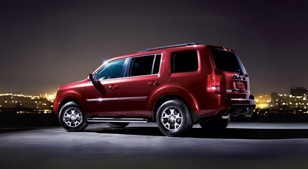 A red 2011 Honda Pilot is shown at night.