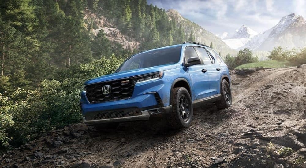 A blue 2023 Honda Pilot Trailsport is shown off-roading.