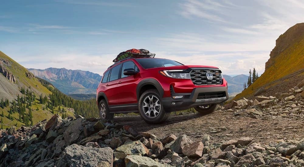 A red 2023 Honda Passport Trailsport shown parked on rocks after visiting a Honda dealer near Bothell, WA.