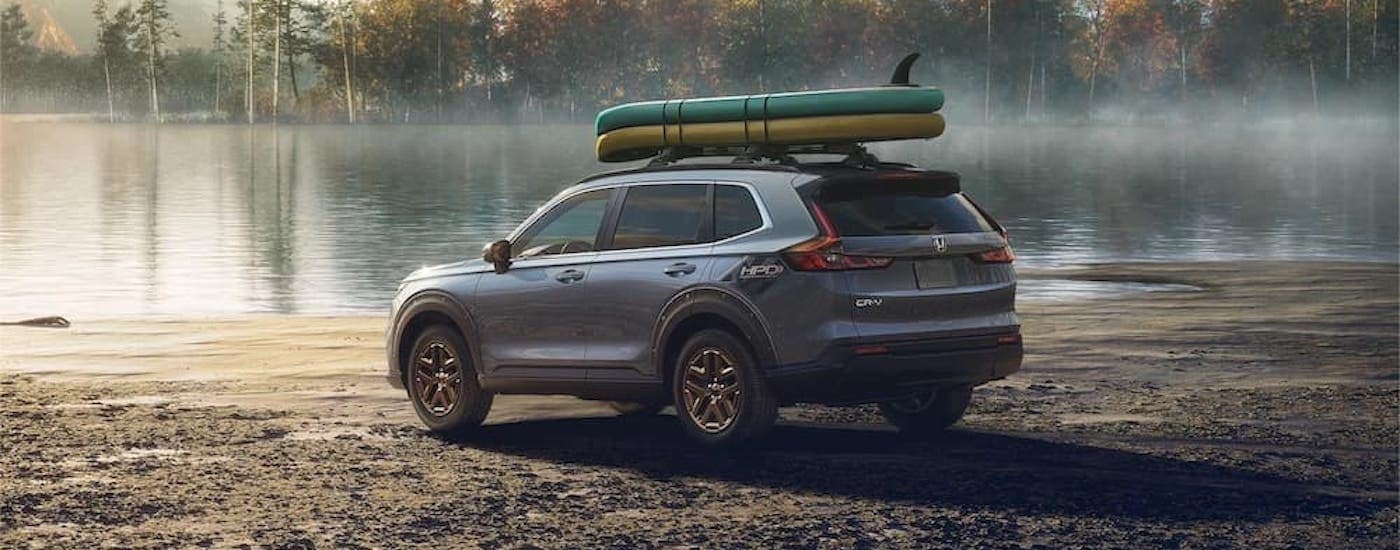 A gray 2023 Honda CR-V is shown from the rear at an angle parked near a lake.