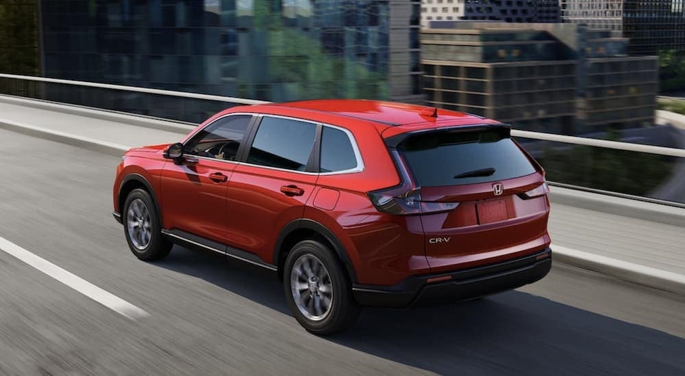 A red 2023 Honda CR-V for sale near Bellevue, WA is shown driving on a highway.