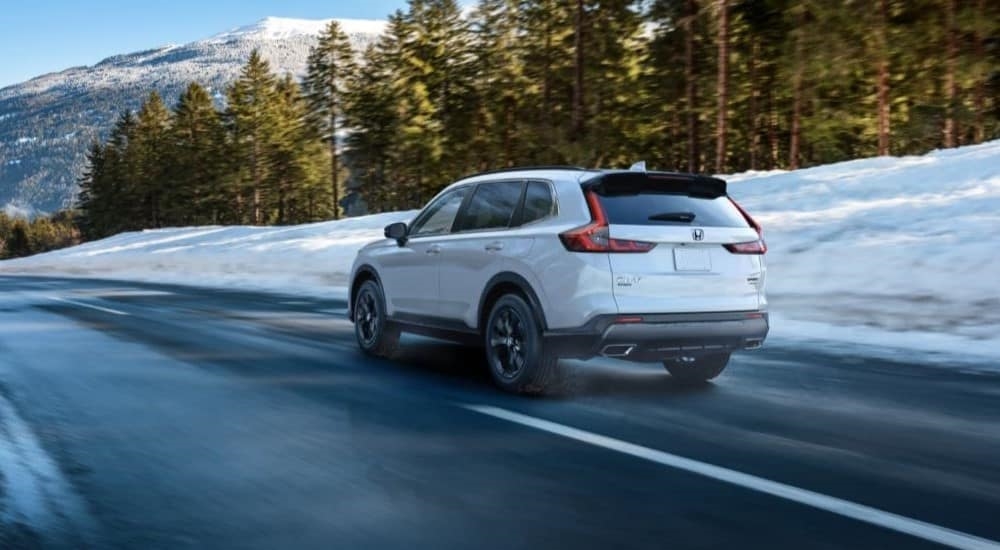 A white 2023 Honda CR-V is shown driving on a highway.