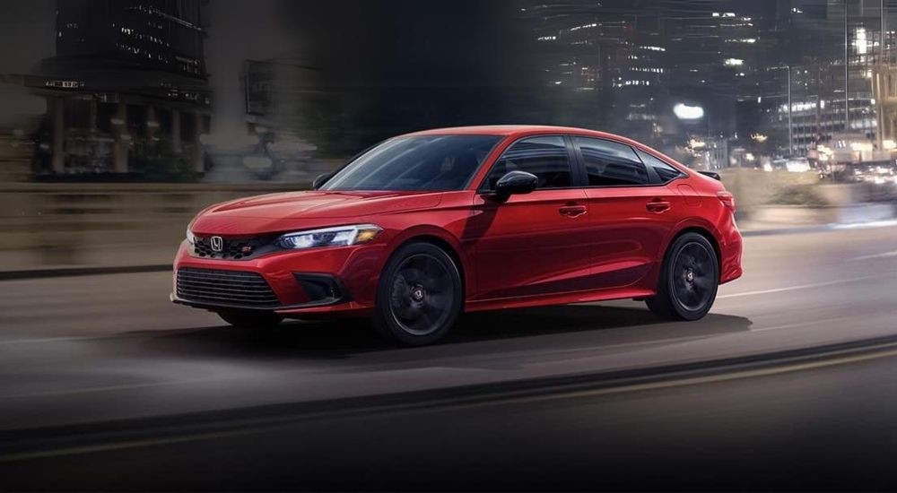 A red 2024 Honda Civic Si is shown on a city street at night after visiting a Honda dealer near Arlington.