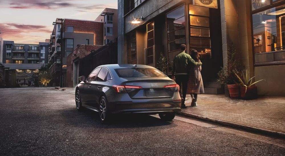 A grey 2024 Honda Civic Touring is shown parked in front of a cafe.