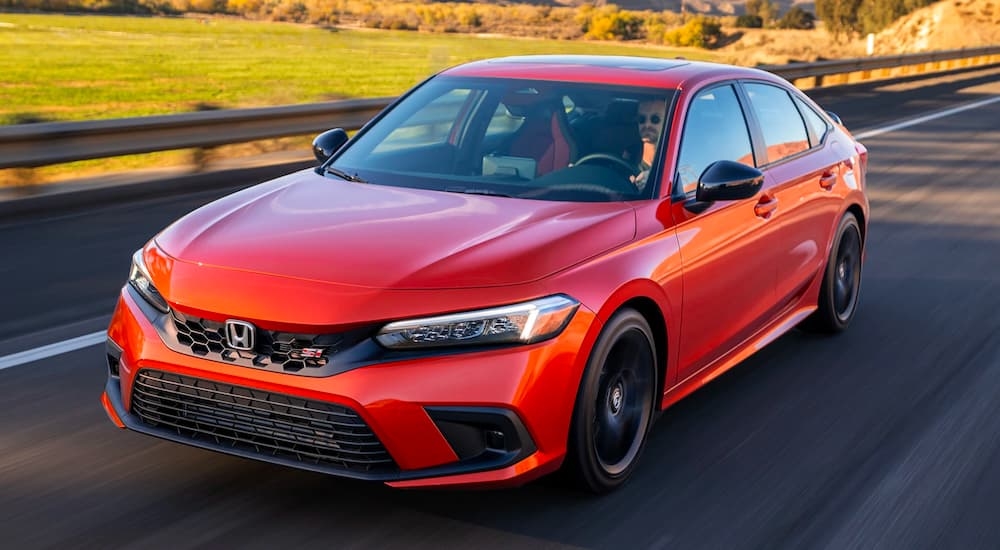An orange 2023 Honda Civic Si is shown driving on an open road after visiting a Honda dealer in Everett, WA.