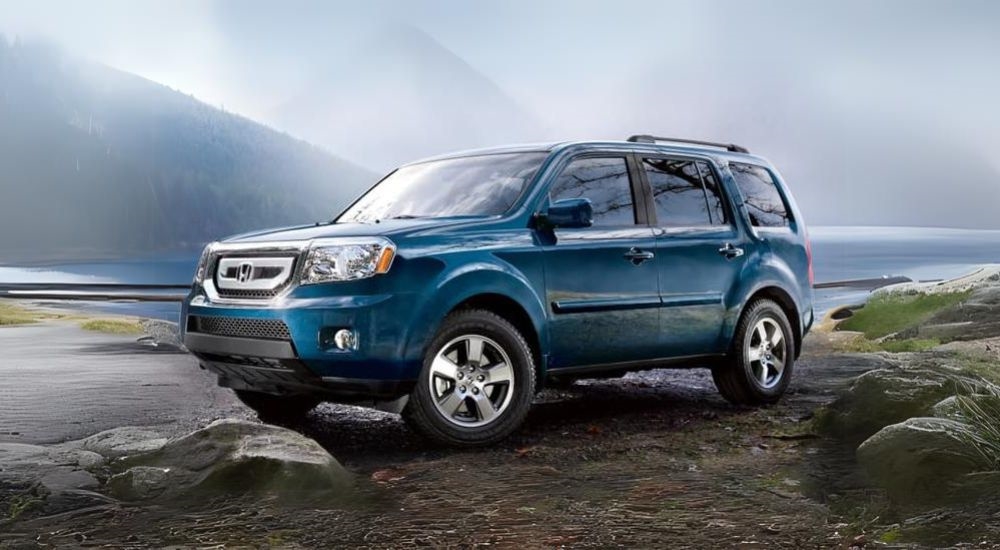 A blue 2011 Honda Pilot is shown at a lake after leaving a Certified Pre-Owned Honda dealership.