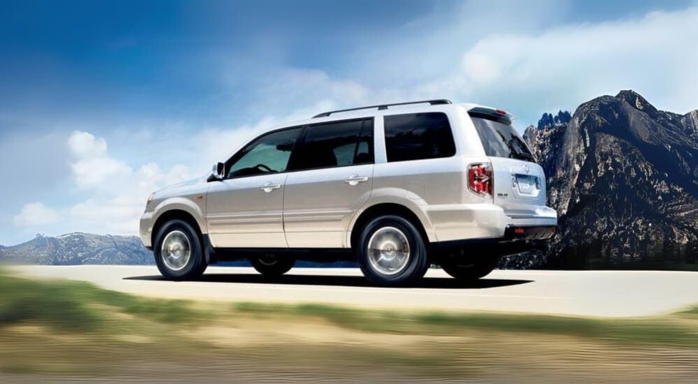 A silver 2008 Honda Pilot is shown driving on a cloudy day.