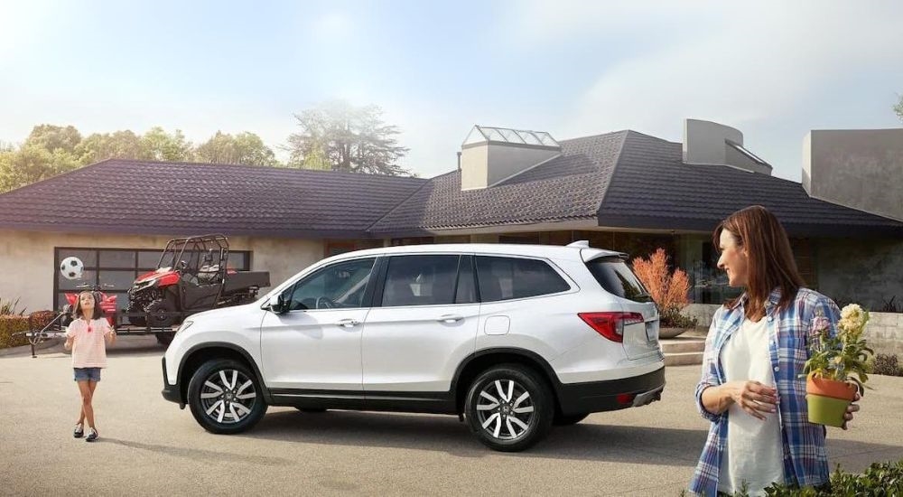A white 2020 Honda Pilot is shown parked on a driveway.