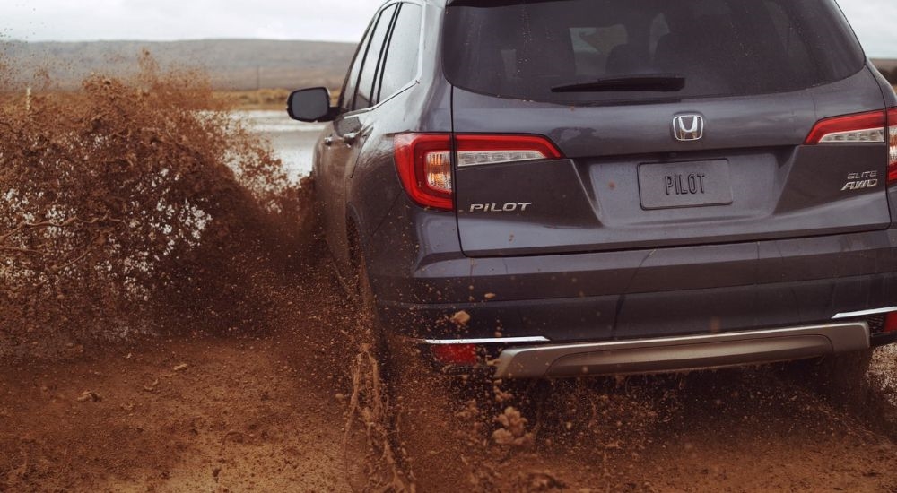 A grey 2020 Honda Pilot is shown kicking up mud after looking for used SUVs for sale.