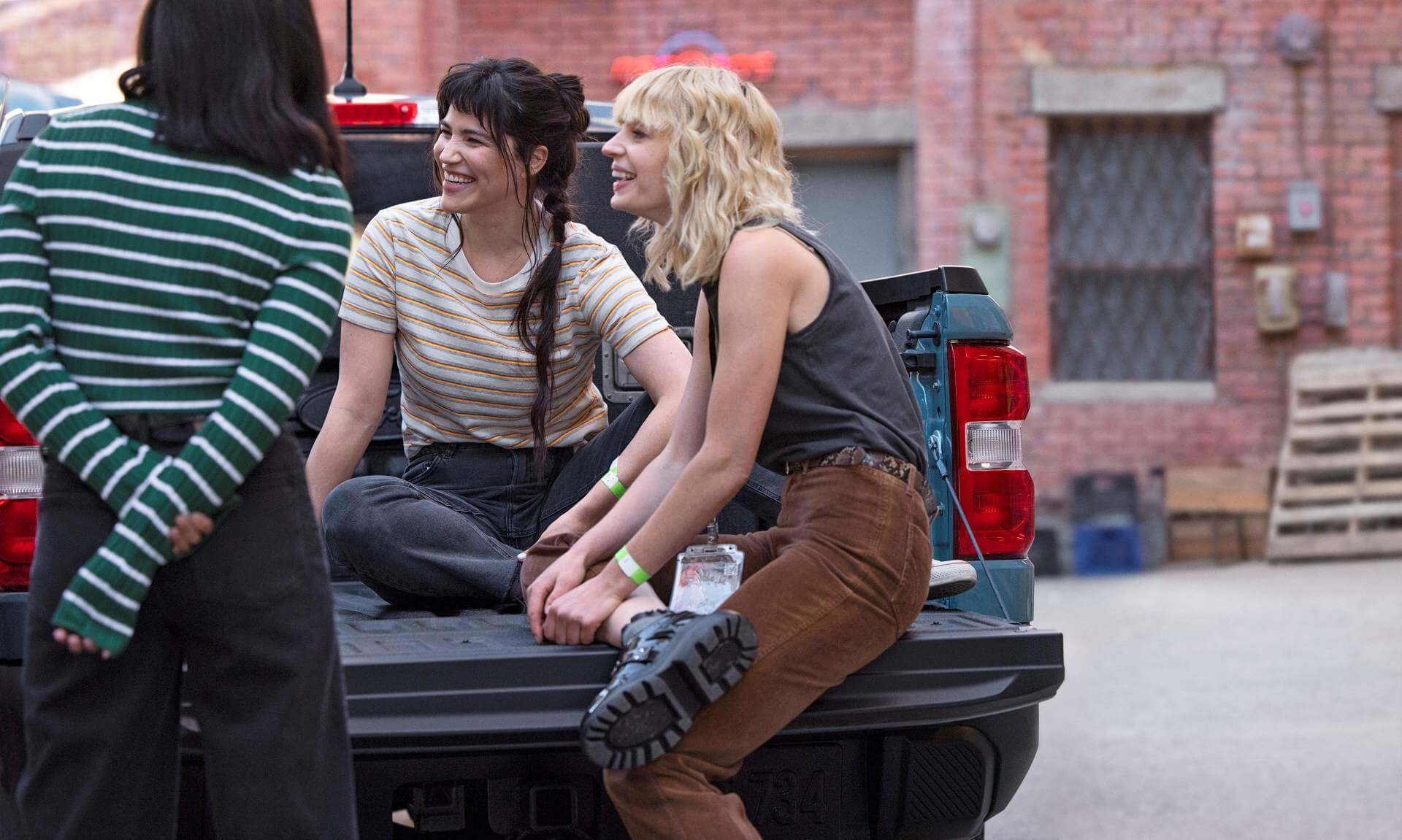 Multiple people sitting on open tailgate of new Ford Maverick.