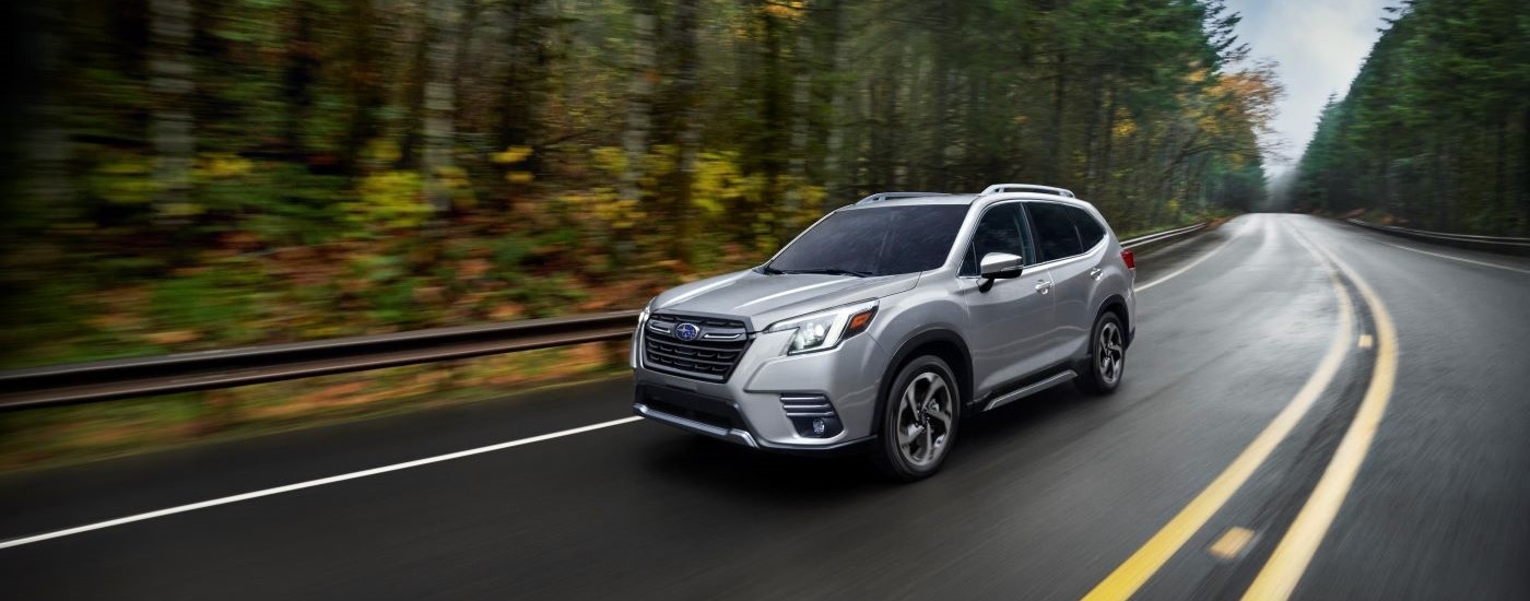 A white 2024 Subaru Forester driving from a dealer with a Subaru Forester for sale near Poughkeepsie.