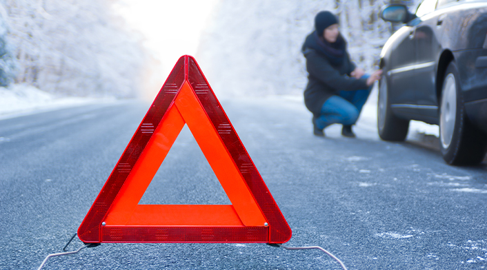 Safety triangle on side of road with car