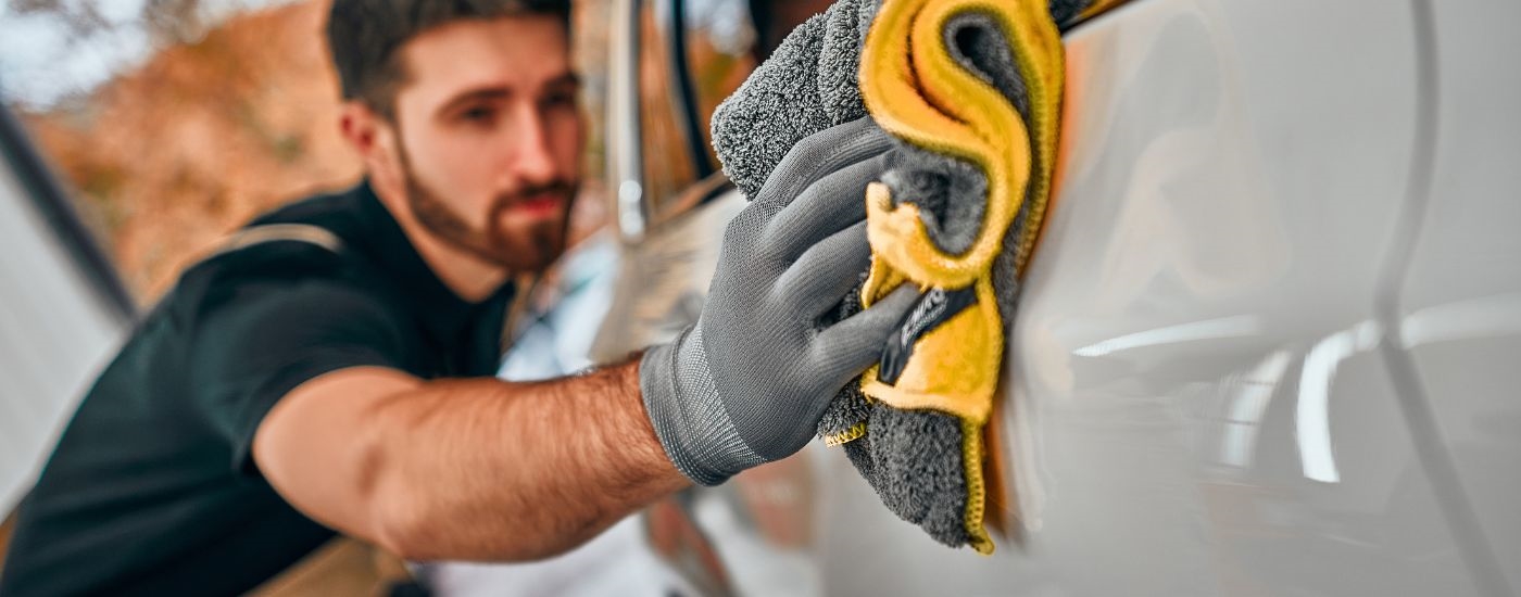 A person is shown detailing a car.