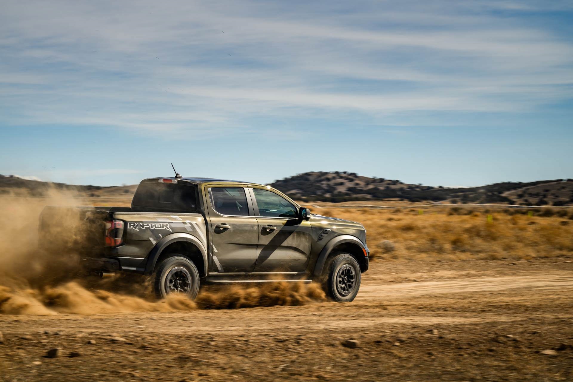 Ford Ranger in Raptor trim kicking up dust on off-road So Cal trail.