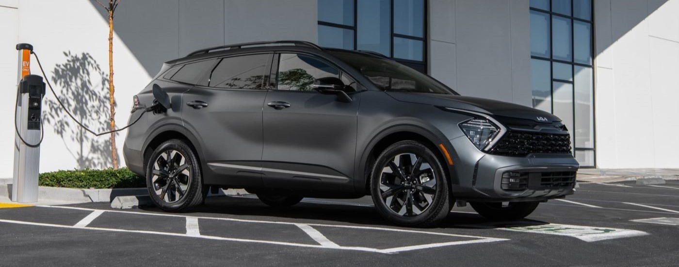 A grey 2023 Kia Sportage PHEV parked at a charging station.