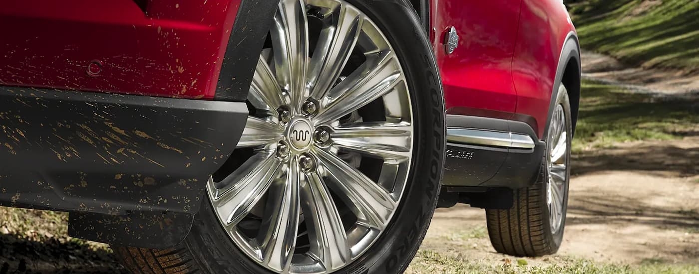 A close-up on the wheels of a red 2024 Ford Explorer King Ranch driving down a dirt road.