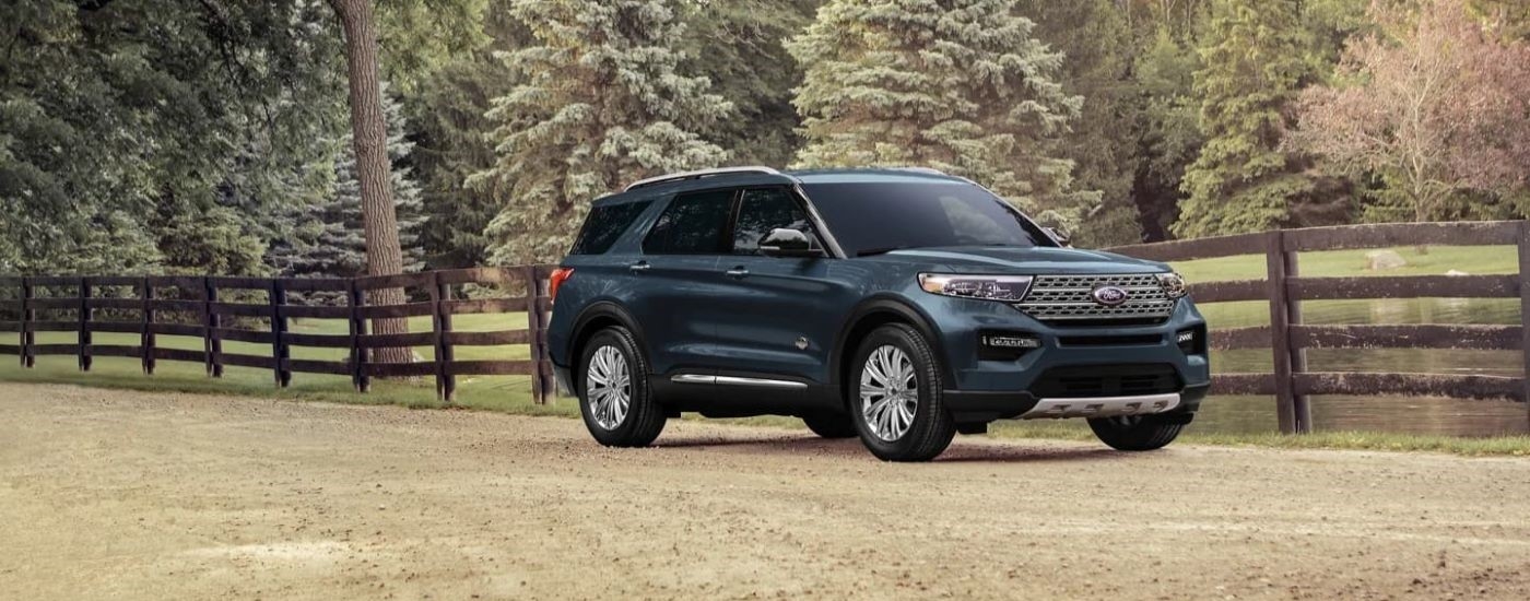 A black 2024 Ford Explorer King Ranch driving by a fence.