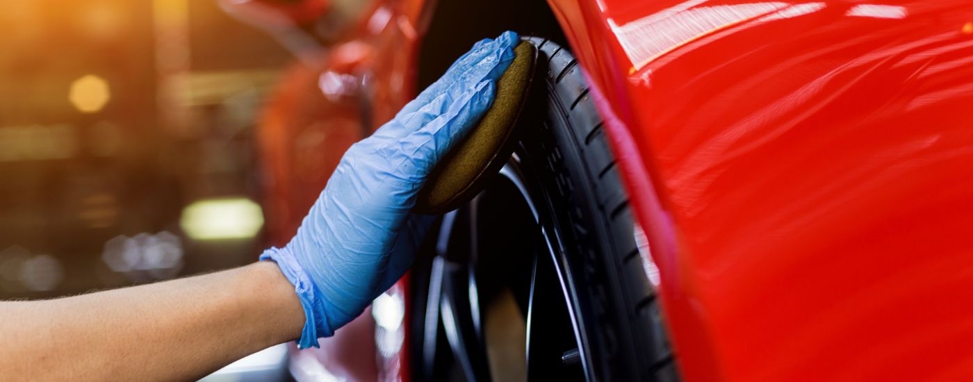 A person is detailing a red car.