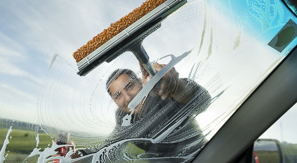 A man is cleaning the windshield of a vehicle with a squeegee.