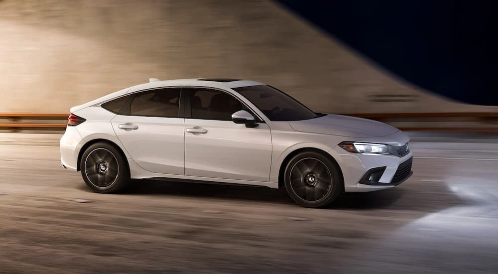 A white 2022 Honda Civic Hatchback is driving on a city street.