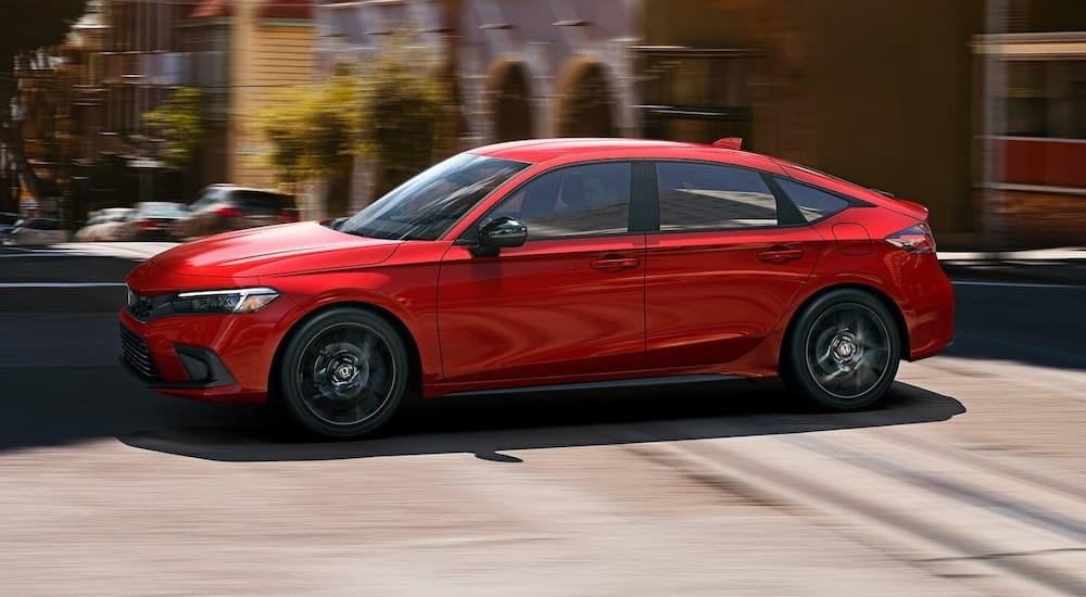 A red 2022 Honda Civic Hatchback is driving through a city street.