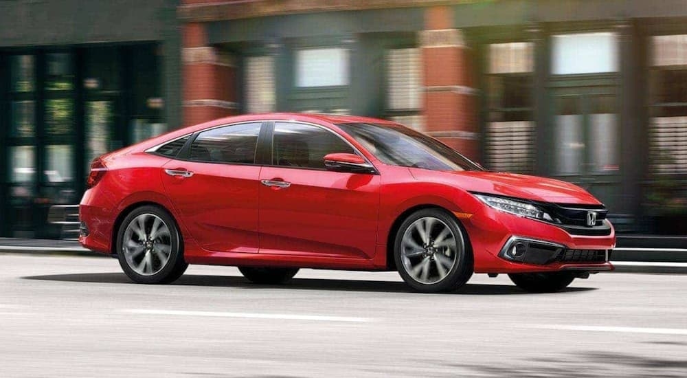 A red 2020 Honda Civic Touring is driving on a city street.