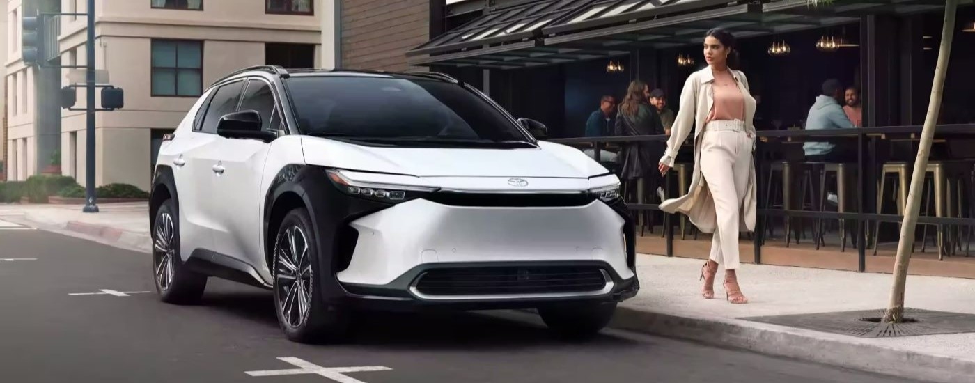 A person is shown walking past a white 2023 Toyota bZ4X Limited near a Toyota Dealer in Yonkers.