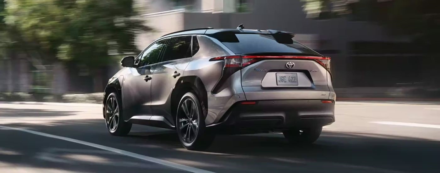 A silver 2024 Toyota BZ4X is shown from the rear at an angle on a city street after leaving a Toyota dealer near Irvington.